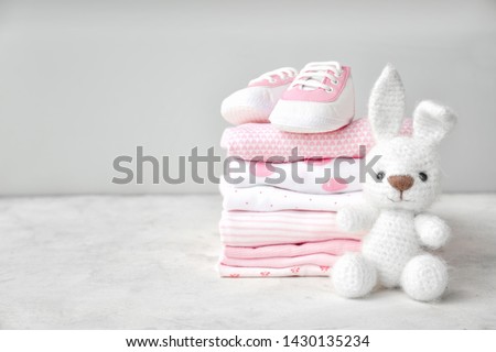 Stack of clothes, shoes and toy on table