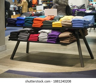 a stack of clothes in the store, pullovers and sweatshirts nicely and neatly stacked in bundles on the table 