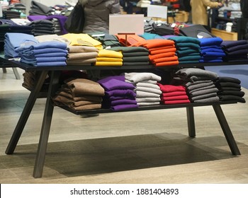 a stack of clothes in the store, pullovers and sweatshirts nicely and neatly stacked in bundles on the table 