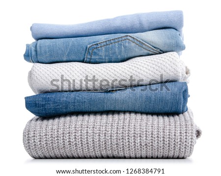 Stack of clothing jeans sweaters on a white background isolation