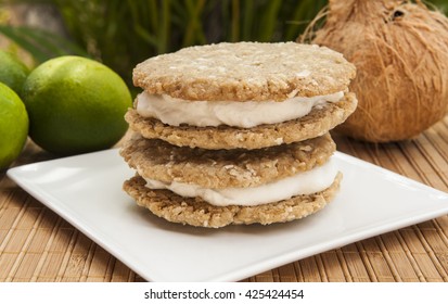 Stack of coconut lime ice cream sandwiches with limes and a coconut