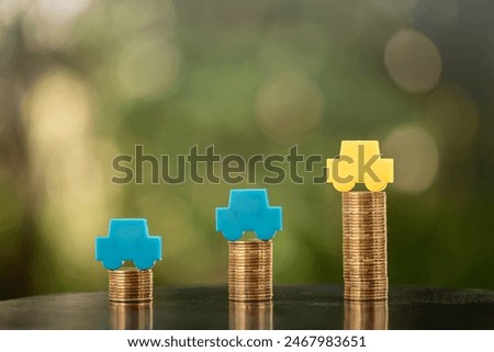 Stack coin with car model with growing on the top for collect interest put on the wood in the public park, loan and saving for buy a new car and business investment a chattel in the future concept.
