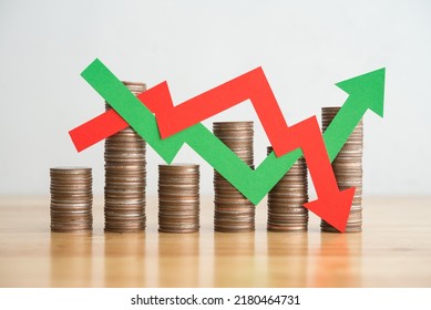 Stack coins and arrow red green graph chart volatility up and down on wooden table background. Business, financial and investment concept. Risk, fluctuation in stock market and bitcoin cryptocurrency.