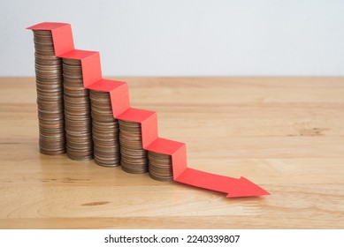 Stack of coins bar chart and red stair graph trending downwards with white wall background on wooden table copy space. Economy recession crisis, inflation, stagflation, business and financial loss. - Shutterstock ID 2240339807