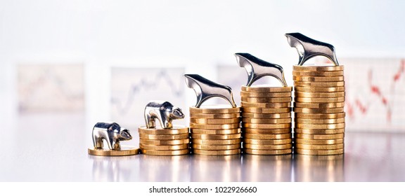 Stack of coins with Bull and Bear and graphics with market prices in the background