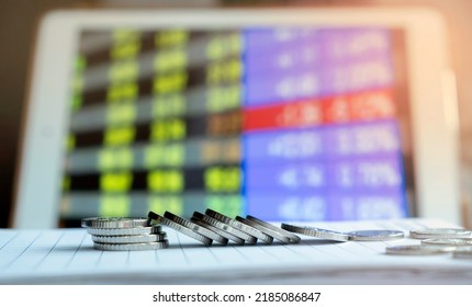 a stack of coins falls on a notebook against the background of a screen with exchange rates. falling exchange rates in the stock market. Coins fell due to inflation