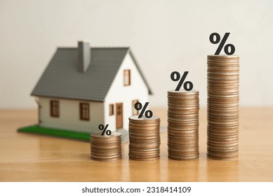 Stack coins as graph trend up and interest rates with house model background. FED fix recession inflation crisis by increase interest rate that effect to house buyer. Mortgage loan, financial concept. - Shutterstock ID 2318414109