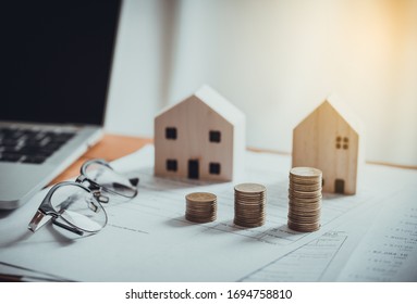 Stack Of Coins With House Model,tax Form,glasses And Tablet,Income Tax Raise Concept.
