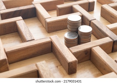 Stack coins in middle of wooden maze game background. Business and financial strategy, investment, stock market, difficult to find or solution making money, budget or money saving planing concept.