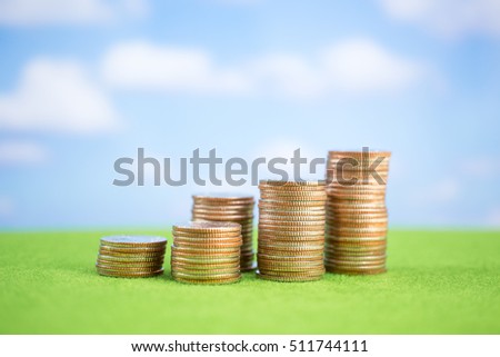 Stack of coins on green and blue sky background