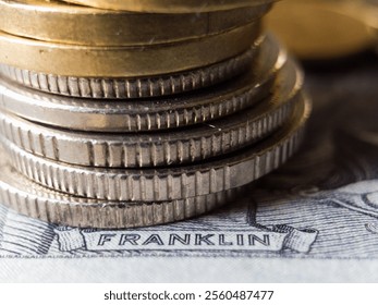 A stack of coins on top of a piece of paper with the word Franklin written on it. The coins are silver and gold