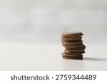 Stack of coins on white table, closeup. Space for text