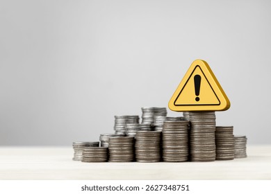 Stack of coins and yellow triangle warning sign, with copy space. Concept of financial risk management, financial urgency, investment analysis and decision making. - Powered by Shutterstock - Get 15% off with code: PIKWIZARD15