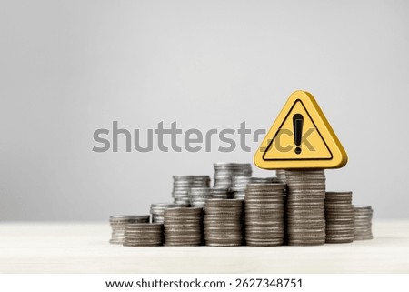 Stack of coins and yellow triangle warning sign, with copy space. Concept of financial risk management, financial urgency, investment analysis and decision making.