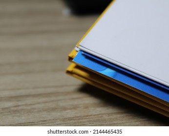 Stack of colored papers on a wooden table.