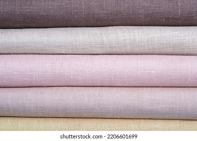 A stack of colored pastel linen fabric, closeup. Linen background. Strips of fabric