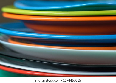 A stack of colored plates close-up on a wooden background.