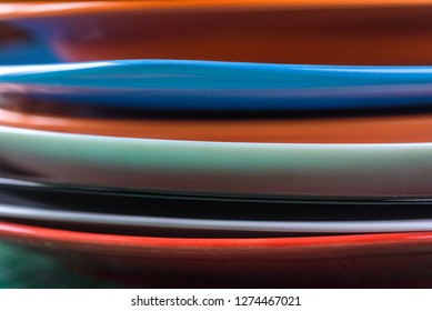 A stack of colored plates close-up on a wooden background.