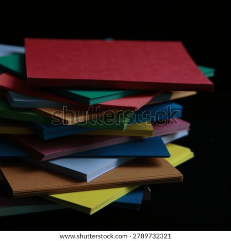 Stack of colorful blank paper sheets arranged in an abstract messy pile on a pitch black background