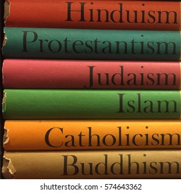 Stack of colorful books of different religions: Islam, Catholicism, Buddhism, Judaism, Protestantism, Hinduism