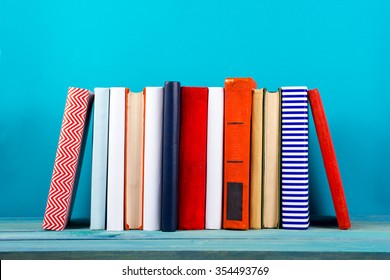 Stack Of Colorful Books, Grungy Blue Background, Free Copy Space Vintage Old Hardback Books On Wooden Shelf On The Deck Table, No Labels, Blank Spine. Back To School. Education Background