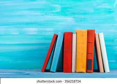 Stack of colorful books, grungy blue background, free copy space Vintage old hardback books on wooden shelf on the deck table, no labels, blank spine. Back to school. Education background