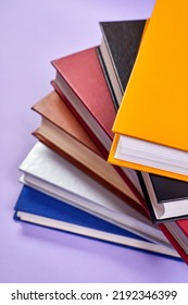 Stack of colorful books on purple background - Shutterstock ID 2192346399