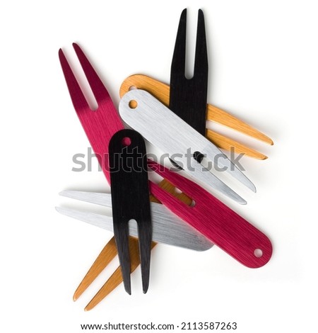Stack of colorful golf divot tool or divot replacers on white background. Flat lay.