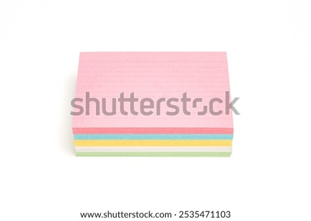 A stack of colorful sticky notes in pink, green, yellow and blue. Pink is on top. Note paper isolated on white background.