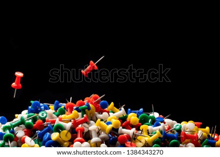 Stack of colorful tacks with two of them falling