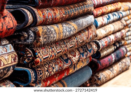Stack of colorful traditional patterned rugs in interior shop
