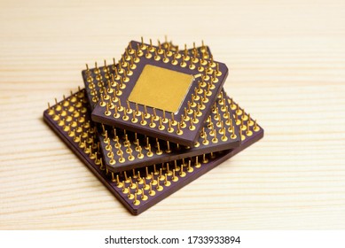 Stack of computer microprocessors with gold contacts on a wooden background. Central Processing Unit. Concept of recycling radio components to produce gold.