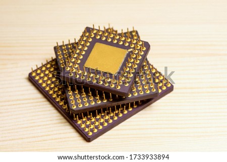 Stack of computer microprocessors with gold contacts on a wooden background. Central Processing Unit. Concept of recycling radio components to produce gold.