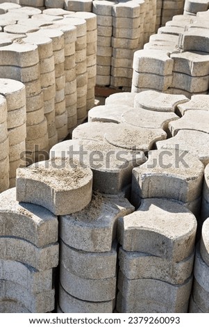 Stack of concrete self locking flooring blocks in curved shape on wooden pallet in a construction site - used in construction industry to create permeable floors to rain water on a layer of sand