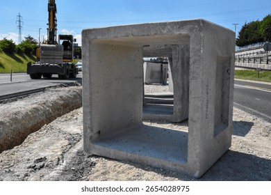 Stack of concrete utility boxes ready for installation at highway construction site