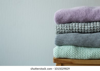 Stack of cozy knitted clothes on a wooden ladder. G