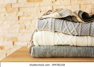 Stack of cozy knitted clothes on a wooden stand.