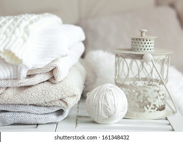 Stack of cozy knitted sweaters and lantern on a table