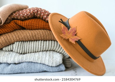 Stack of cozy knitted warm sweater with Autumn fall maple leaf and beige stylish hat. Sweaters in retro Style. Orange and blue colors. Cozy hygge concept Copy space Autumn season - Powered by Shutterstock