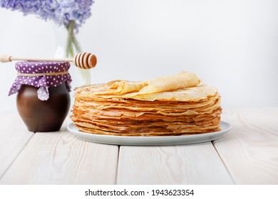 Stack Of Crepes With Honey Clay Jug And Spring Flowers On Wooden Table. Side View, Copy Space.