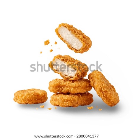 Stack of Crispy Chicken Nuggets with Floating Half Cut and Crumbs Isolated on White Background