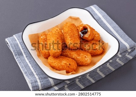 Stack of crispy fried glutinous rice cakes with oozing black brown sugar filling in a bowl, dark wooden background
