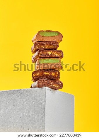 Stack of cut chocolates with different fillings on colored background, hero view
