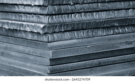 Stack of dark blue thick heavy metal plates rusty uneven surface after laser cutting. plates stacked top each other, creating sense depth and texture. scene is somewhat dark industrial blue background