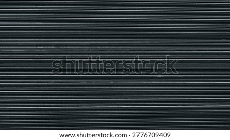 stack of dark composite decking boards, focusing on the repetitive linear texture and rhythmic pattern