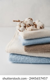 Stack of delicate colored cotton towels with cotton buds on white background
