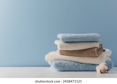 Stack of delicate colored cotton towels with cotton buds on  blue background