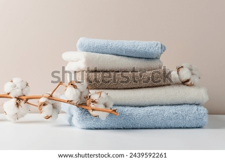 Stack of delicate colored cotton towels with cotton buds on a beige background