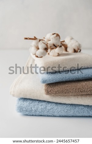 Stack of delicate colored cotton towels with cotton buds on white background