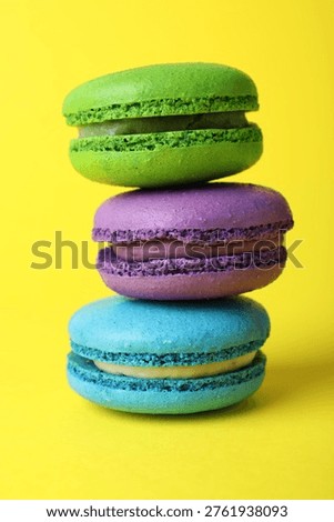 Stack of delicious colorful macarons on yellow background, closeup